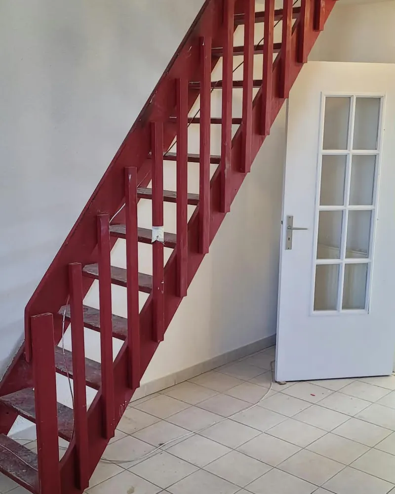 Ancien escalier en bois peint en rouge, avec garde-corps à barreaux en bois
